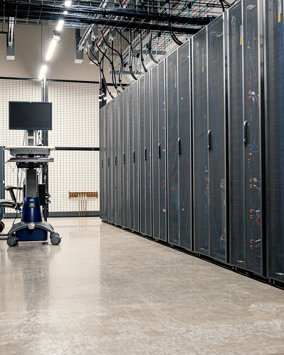 A secure data center corridor with rows of server racks and an operator workstation